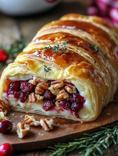 a cranberry and pecan roll on a wooden cutting board with christmas decorations around it