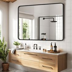 a bathroom with two sinks and a large mirror over the sink, along with a potted plant