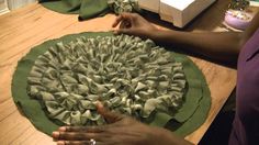 a woman is working with fabric on a table