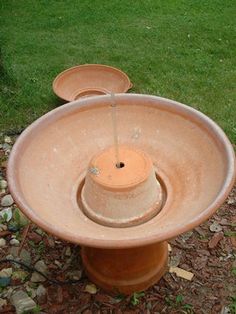 an old water fountain is sitting on the ground in front of some grass and rocks