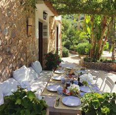 an outdoor table with plates and flowers on it