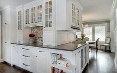 a kitchen with white cabinets and black counter tops, along with wooden flooring that matches the hardwood floors