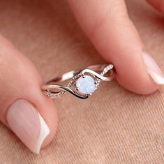 a woman's hand holding a white opal ring