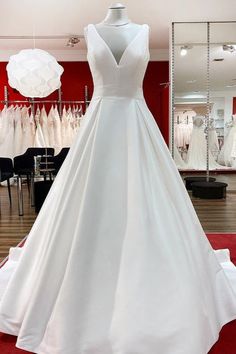 a white wedding dress on display in a bridal room with red carpet and mannequins