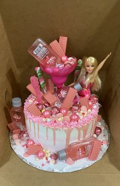 a barbie doll sits on top of a cake with pink icing and candy decorations