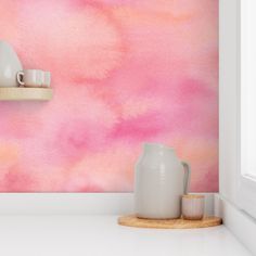 a pink and white painted wall with two vases on the shelf next to it