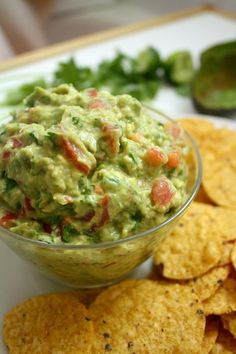 a bowl of guacamole surrounded by tortilla chips on a plate