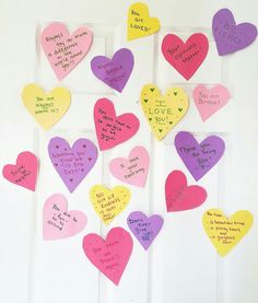 a bunch of paper hearts that have been pinned to the wall with writing on them