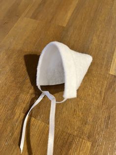 a piece of white material sitting on top of a wooden floor next to a ribbon