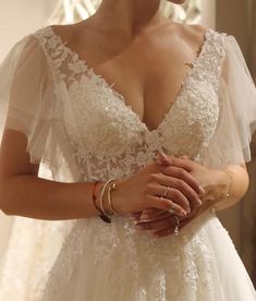 a woman in a wedding dress holding her hands together