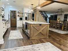 a large kitchen with wooden floors and white cabinets in the center, along with an open floor plan