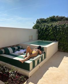 a woman laying on top of a green and white couch next to a swimming pool