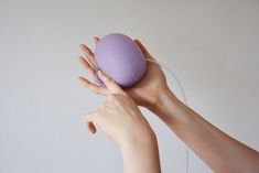 a woman holding an egg in her hands with one hand and the other on top of it