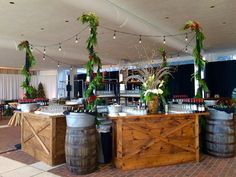 the bar is decorated with greenery and wine barrels as well as flowers on display