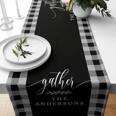 a black and white checkered table runner with the name gather on it, along with flowers