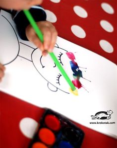 a child is drawing with colored pencils on a paper