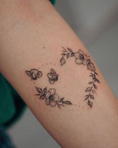 a woman's arm with flowers and butterflies in the shape of a heart on it