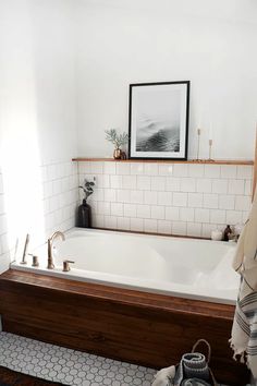 a bathroom with a bathtub, rugs and pictures on the wall above it