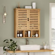 a wooden cabinet above a white sink in a room with green walls and flooring