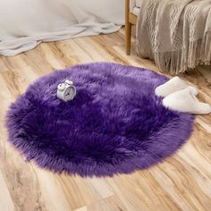 a purple round rug on the floor in a room with wooden floors and white pillows