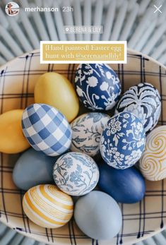 a bowl filled with painted eggs on top of a table