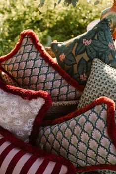 several pillows are stacked on top of each other in front of some bushes and trees