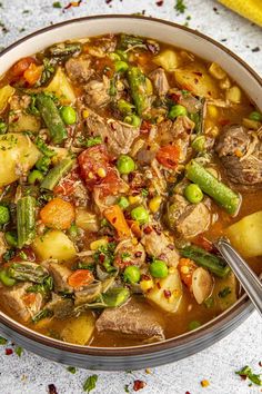 a bowl filled with meat and vegetables on top of a table next to a spoon