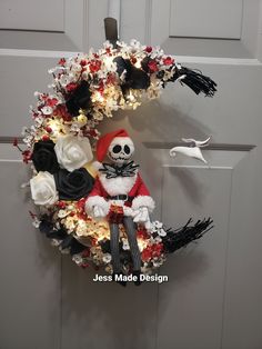 a wreath decorated with white and red flowers, black and white decorations and a santa hat