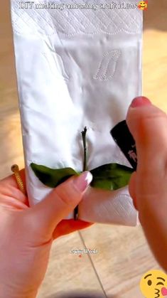 a person holding up a napkin with a flower on it's side and an embellishment in the middle