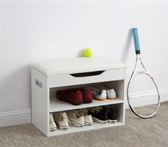 a tennis racket and shoes are sitting on a shelf next to a white wall