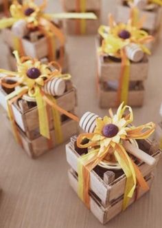 small wooden boxes with candy wrapped in yellow and orange ribbons on top of a table