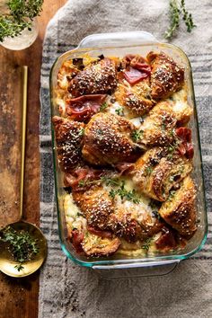 a casserole dish with meat and cheese in it on a table next to a spoon