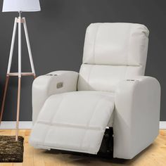 a white recliner chair sitting on top of a wooden floor next to a lamp