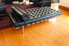 a black leather couch sitting on top of a hard wood floor next to a glass table