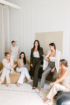 a group of women sitting around each other in front of a wall with white walls