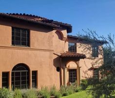 a large house with many windows and plants in the front yard