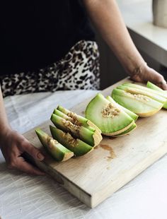 someone cutting up some fruit on a wooden board