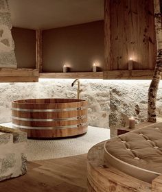 a large wooden tub sitting in the middle of a bathroom next to a stone wall