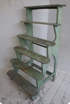 an old green wooden shelf with two benches on the bottom and one bench below it