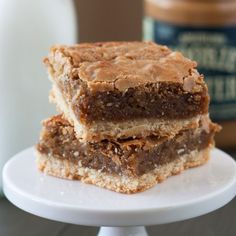 three pieces of brownies stacked on top of each other with peanut butter in the background