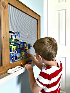 a young boy is playing with legos on the wall in his room, as he looks at it