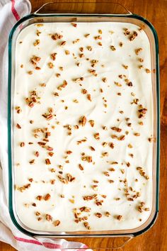 a glass baking dish filled with white frosting and pecans scattered around the edges