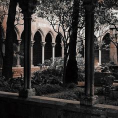 an old building with arches and trees in the courtyard, surrounded by plants and flowers