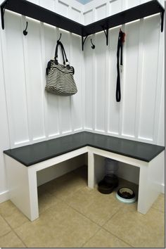 a white bench with a black seat and two coats hanging from it's sides