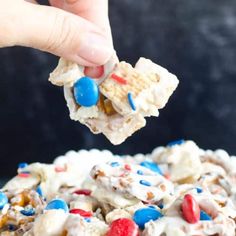 a hand holding a piece of white chocolate with red, white and blue sprinkles