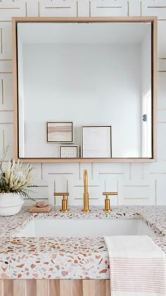 a bathroom sink with a mirror above it and gold faucets on the counter