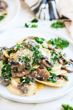 a white plate topped with ravioli covered in mushrooms