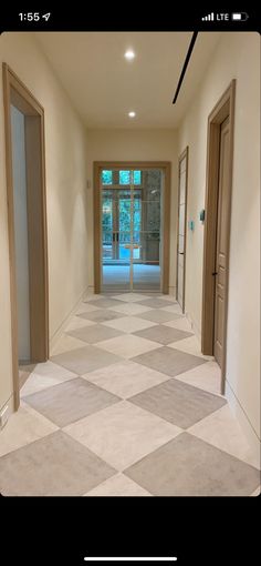 an empty hallway with two doors leading to another room and the floor is tiled in white