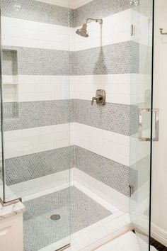 a white and gray tiled bathroom with glass shower doors