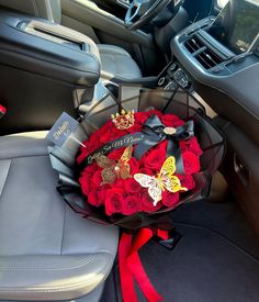 a bouquet of red roses in the back seat of a car with gold butterflies on it